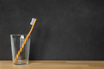 Image showing a wooden toothbrush in a glass on black background