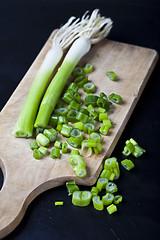 Image showing Fresh green organic chopped onions on a cutting board.