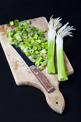 Image showing Fresh green organic chopped onions and knife on a cutting board.