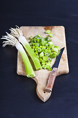 Image showing Fresh green organic chopped onions and knife on a cutting board.
