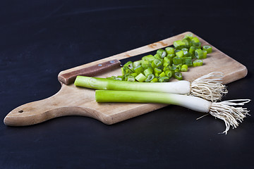 Image showing Fresh green organic chopped onions and knife on a cutting board.