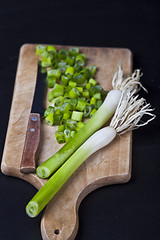 Image showing Fresh green organic chopped onions and knife on a cutting board.