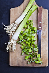 Image showing Fresh green organic chopped onions and knife on a cutting board.