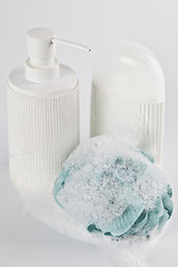 Image showing Liquid soap, lotion, green sponge and foam on light background.