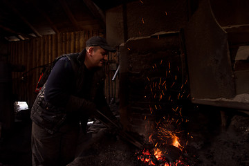 Image showing young traditional Blacksmith working with open fire