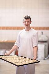 Image showing A young baker holding raw product of white dough