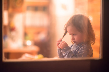 Image showing little cute girl playing near the window