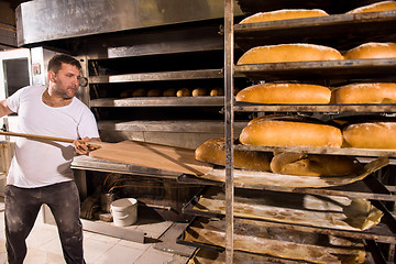 Image showing bakery worker taking out freshly baked breads