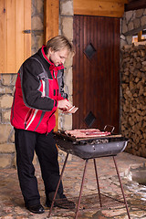 Image showing young man cooking meat on barbecue