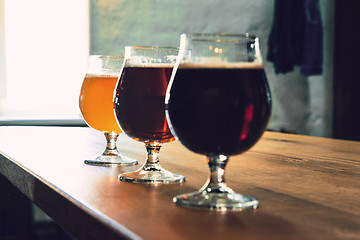 Image showing Glasses of different kinds of beer on wooden background