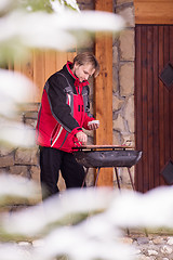 Image showing young man cooking meat on barbecue