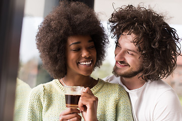 Image showing happy multiethnic couple relaxing at modern home indoors