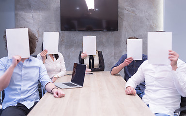 Image showing startup business team holding a white paper over face