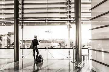 Image showing Young woman waiting at airport, looking through the gate window.