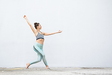 Image showing Fit sporty active girl in fashion sportswear doing yoga fitness exercise in front of gray wall, outdoor sports, urban style