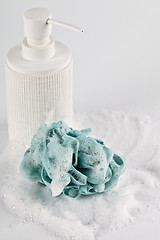 Image showing Liquid soap, green sponge and foam on light background.