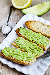 Image showing Croutons with avocado guacamole on white plate closeup on rustic