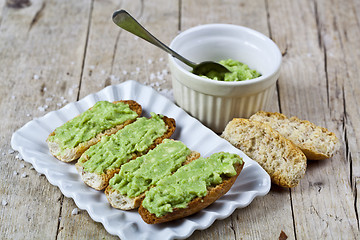 Image showing Crostini with avocado guacamole on white plate closeup on rustic