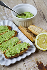 Image showing Toasts with avocado guacamole on white plate closeup on rustic w