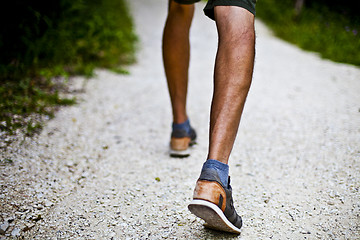 Image showing Low angle ground level view with feet of a man on park or forest