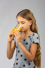 Image showing A ten-year-old girl drinks juice, half-sided view