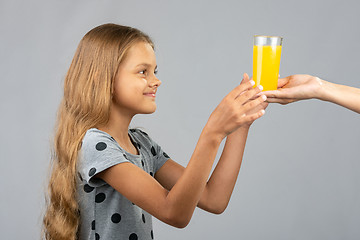 Image showing A girl with two hands takes a glass of juice from the hand of another person