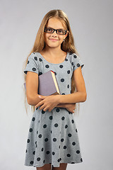 Image showing Schoolgirl in glasses stands with a book in her hands