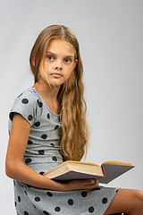 Image showing A girl of ten years distracted from reading a book and looked at the frame