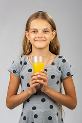 Image showing A girl holds a glass of juice in her hands with both hands