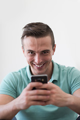 Image showing young man using a mobile phone  at home