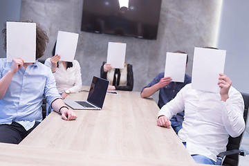 Image showing startup business team holding a white paper over face