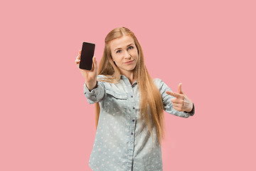 Image showing Portrait of a confident casual girl showing blank screen mobile phone isolated over pink background