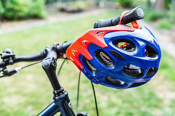 Image showing Bike helmet hangs from the handlebars of a bicycle