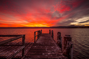 Image showing Burning red sunset  on the lake with timber jetty