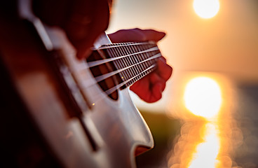 Image showing Woman at sunset playing the ukulele