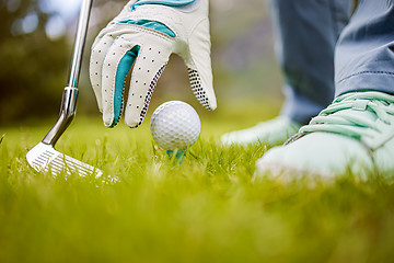 Image showing Hand in glove placing golf ball on tee