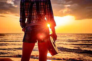 Image showing Woman at sunset holding a ukulele