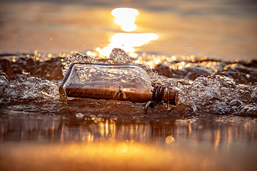 Image showing Message in the bottle against the Sun setting down