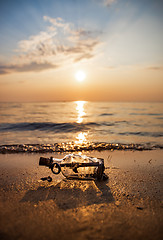 Image showing Message in the bottle against the Sun setting down