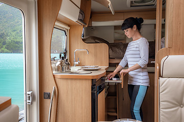 Image showing Woman cooking in camper, motorhome interior