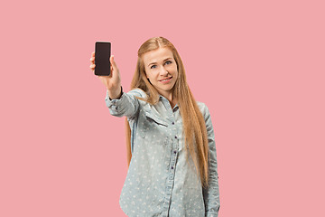 Image showing Portrait of a confident casual girl showing blank screen mobile phone isolated over pink background