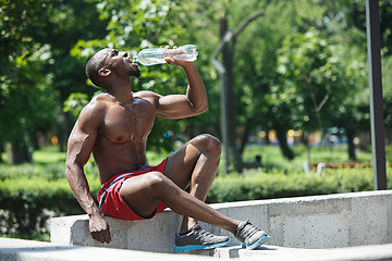 Image showing Athlete resting and drinking water after exercises at stadium