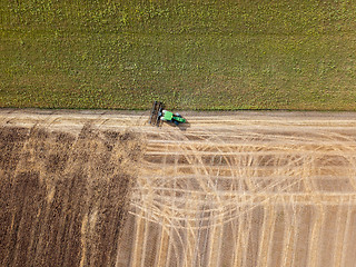 Image showing Panoramic view of tractor plowing the soil after harvesting on the field. Top view from drone.