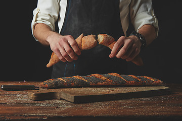 Image showing Hand breaks baguette