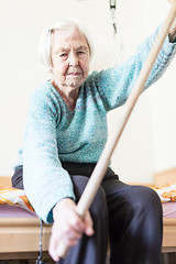 Image showing Elderly 96 years old woman exercising with a stick sitting on her bad.