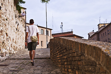 Image showing Back view of a man tourist walking in ancient town.