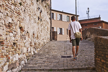 Image showing Back view of a man tourist walking in ancient town.