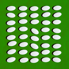 Image showing White pills on green background. 