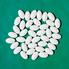 Image showing White pills group on teal green background. 