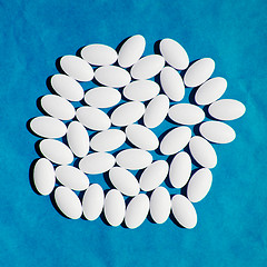 Image showing White vitamin pills group on blue background.